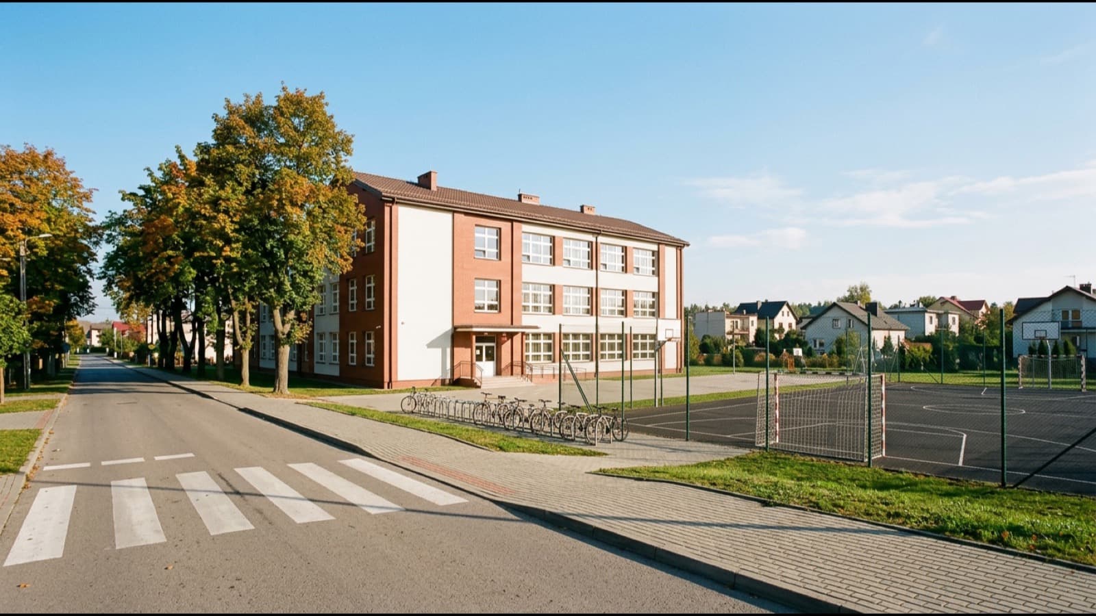 Szkoła podstawowa z boiskiem i chodnikiem prowadzącym do pobliskiego osiedla
